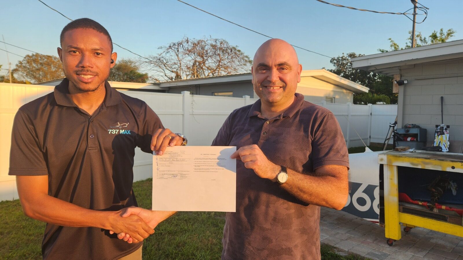 A&P graduate shaking hands with instructor Kivilcim Ozaner beside an aircraft after certification